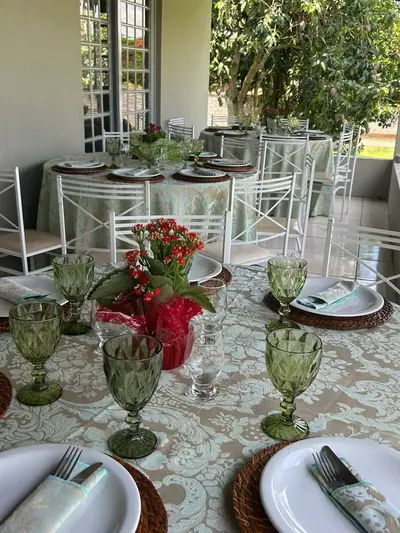 Mesa posta com taças verdes e flores vermelhas em confraternização de empresa