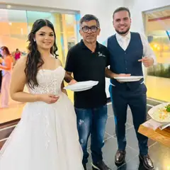 Gilson entre os noivos, que seguram os pratos no buffet do casamento