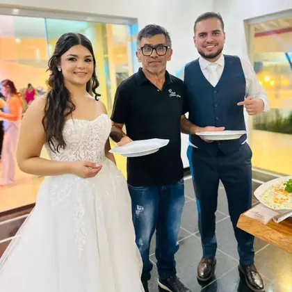 Gilson entre os noivos, que seguram os pratos no buffet do casamento