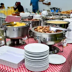 Réchauds com pratos quentes e pilha de pratos no buffet