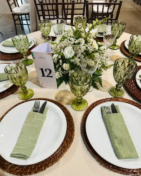 Mesa posta com sousplat de palha, guardanapo verde e arranjo de flores brancas em casamento atendido pelo Buffet Gilson Festas