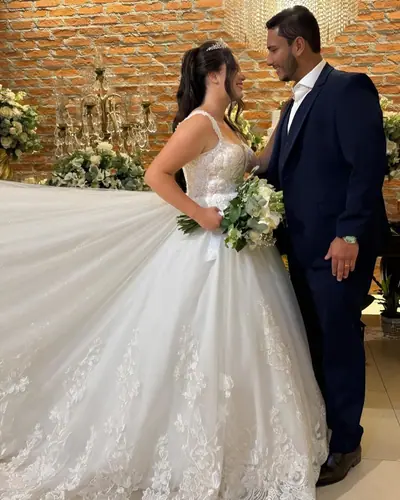 Noivos de mãos dadas no salão, vestido com cauda longa